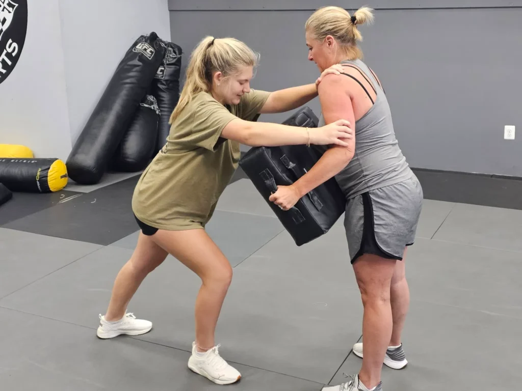 Two women practicing Krav Maga self-defense tactics, improving their confidence and defense skills. Guardian Krav Maga LLC offers tailored programs for women's self-defense.